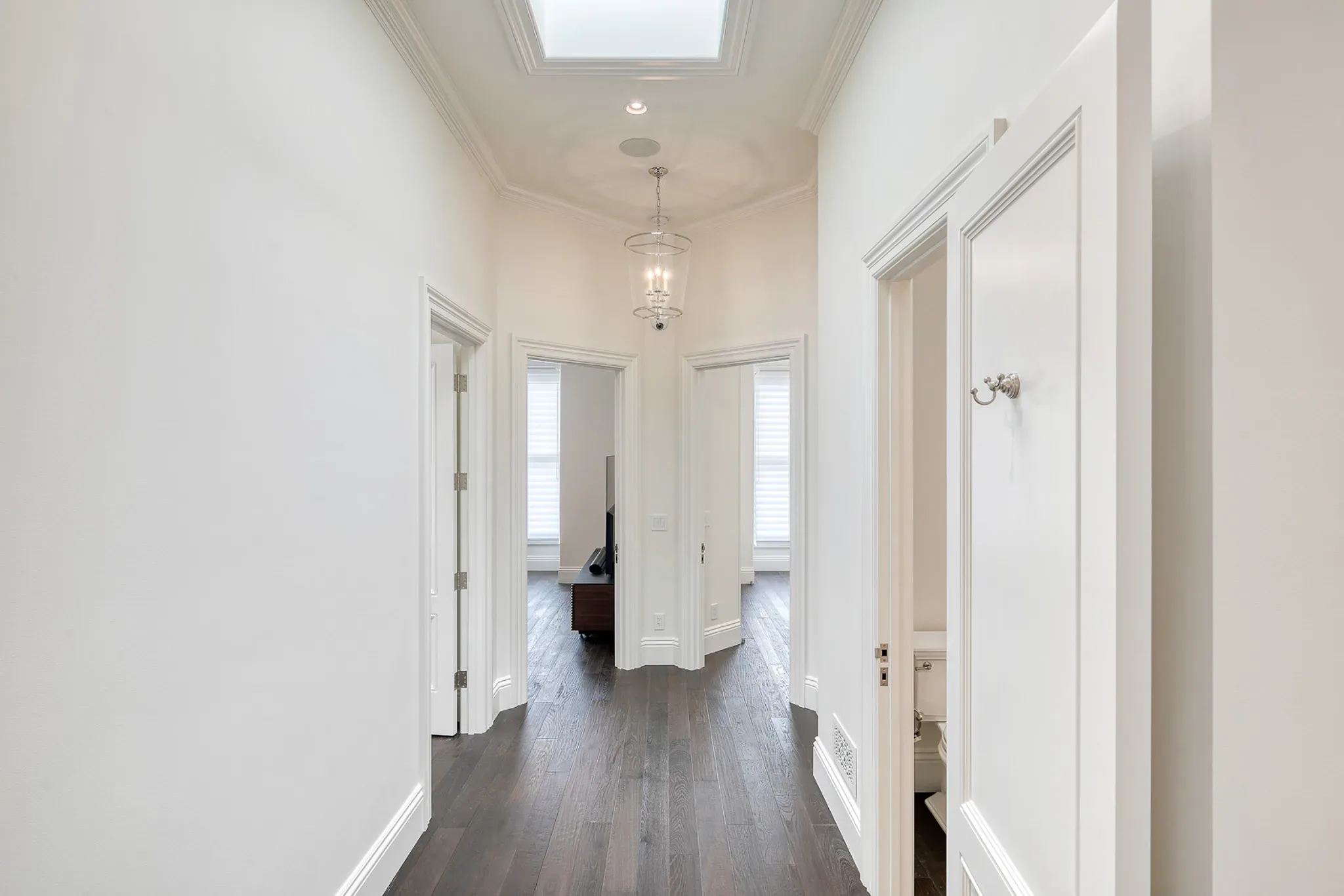 A white hallway with hardwood floors and a skylight.
