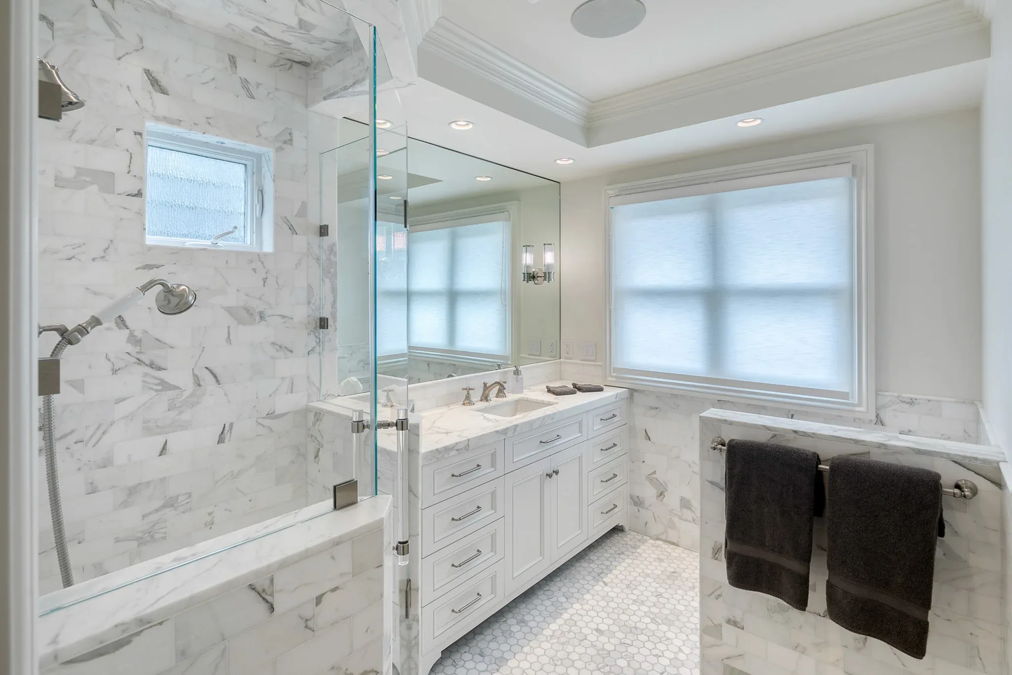 A white bathroom with marble floors and a glass shower.