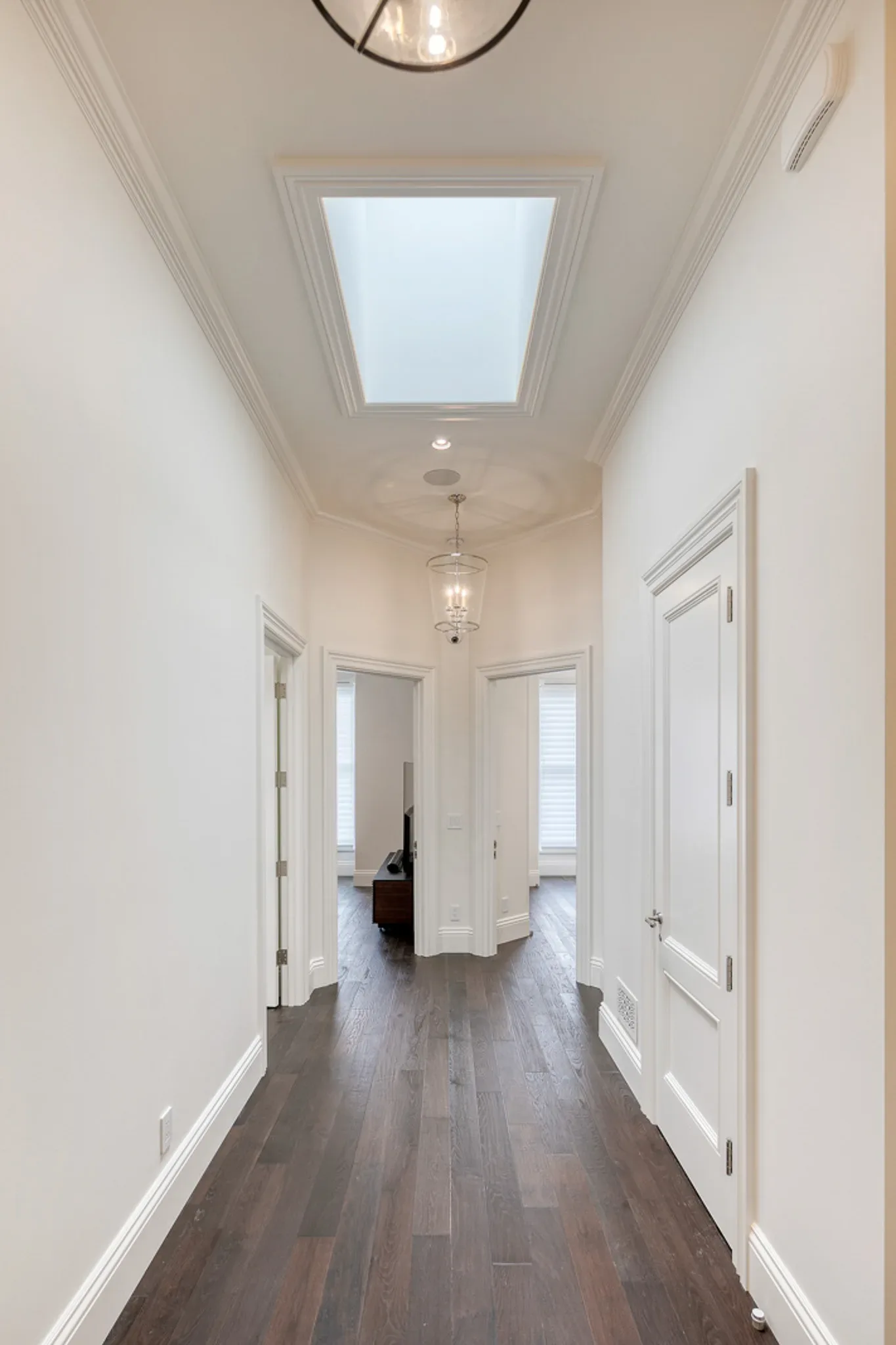 A hallway with hardwood floors and a skylight.