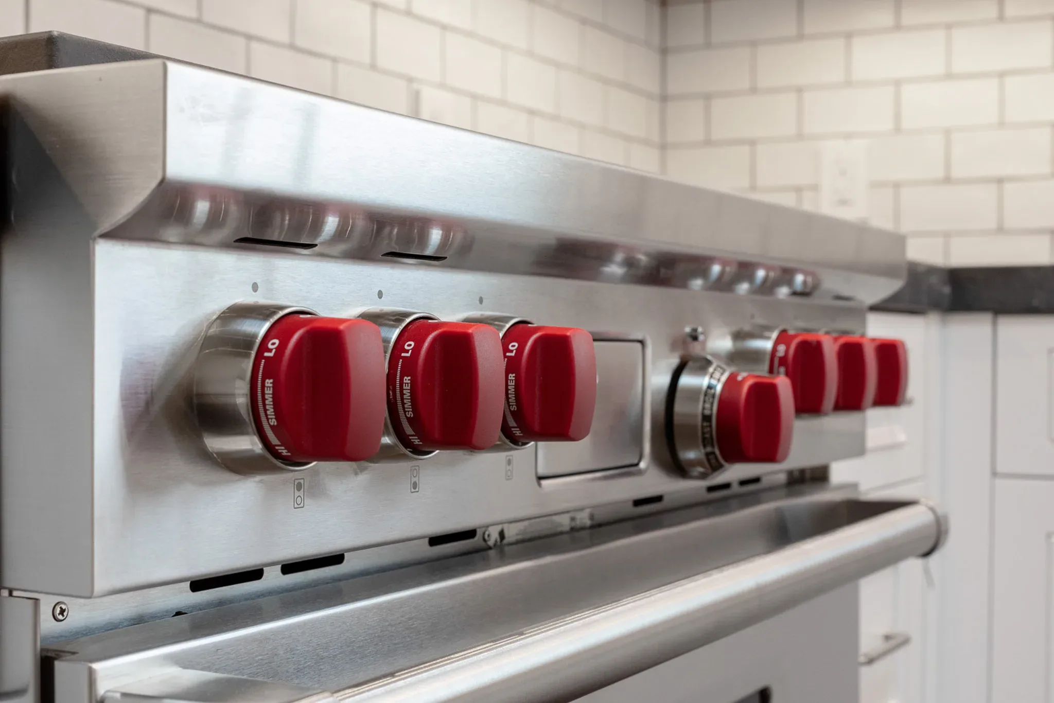 Red knobs on a stainless steel oven.