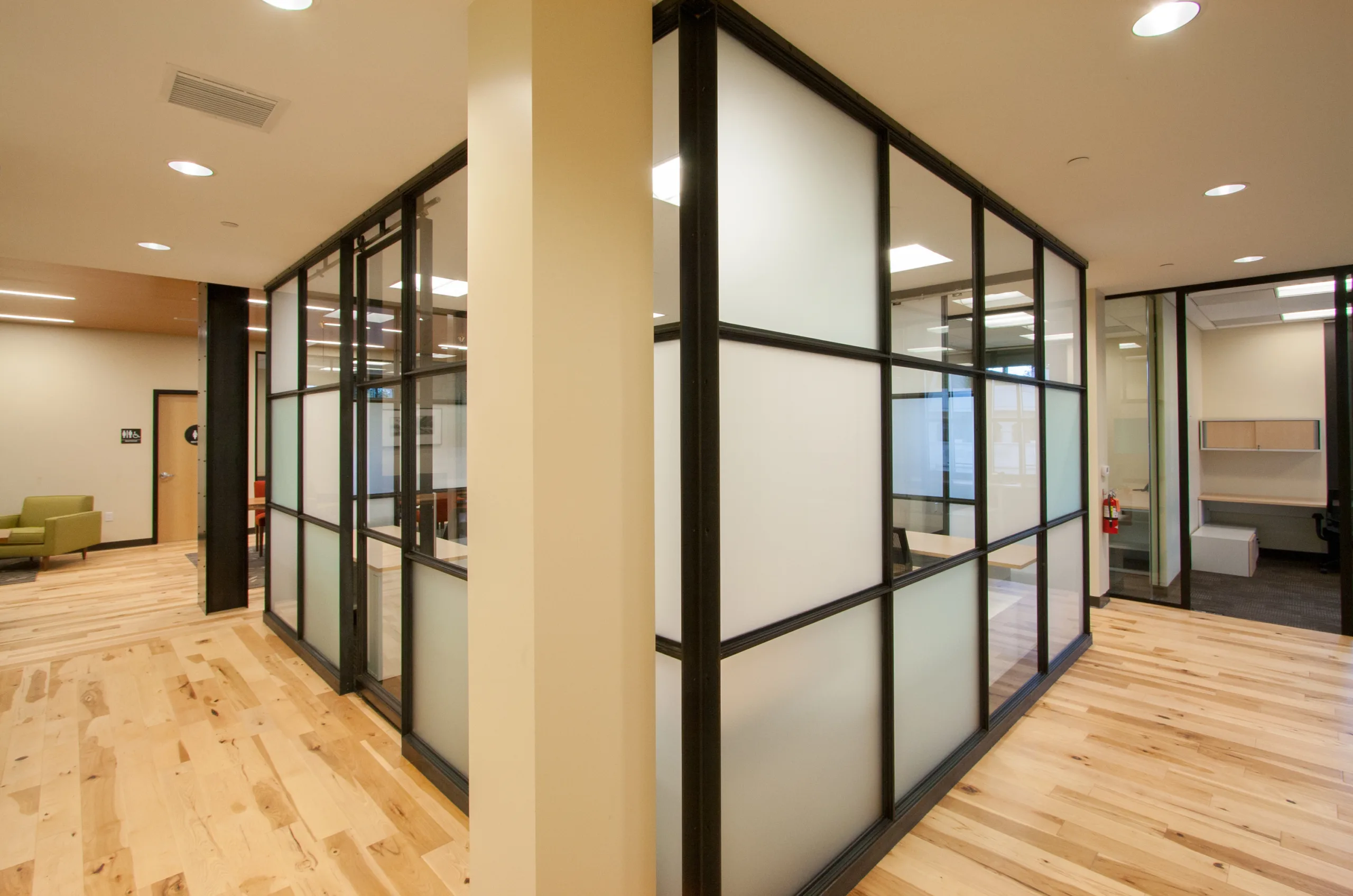 An office with glass partitions and hardwood floors.
