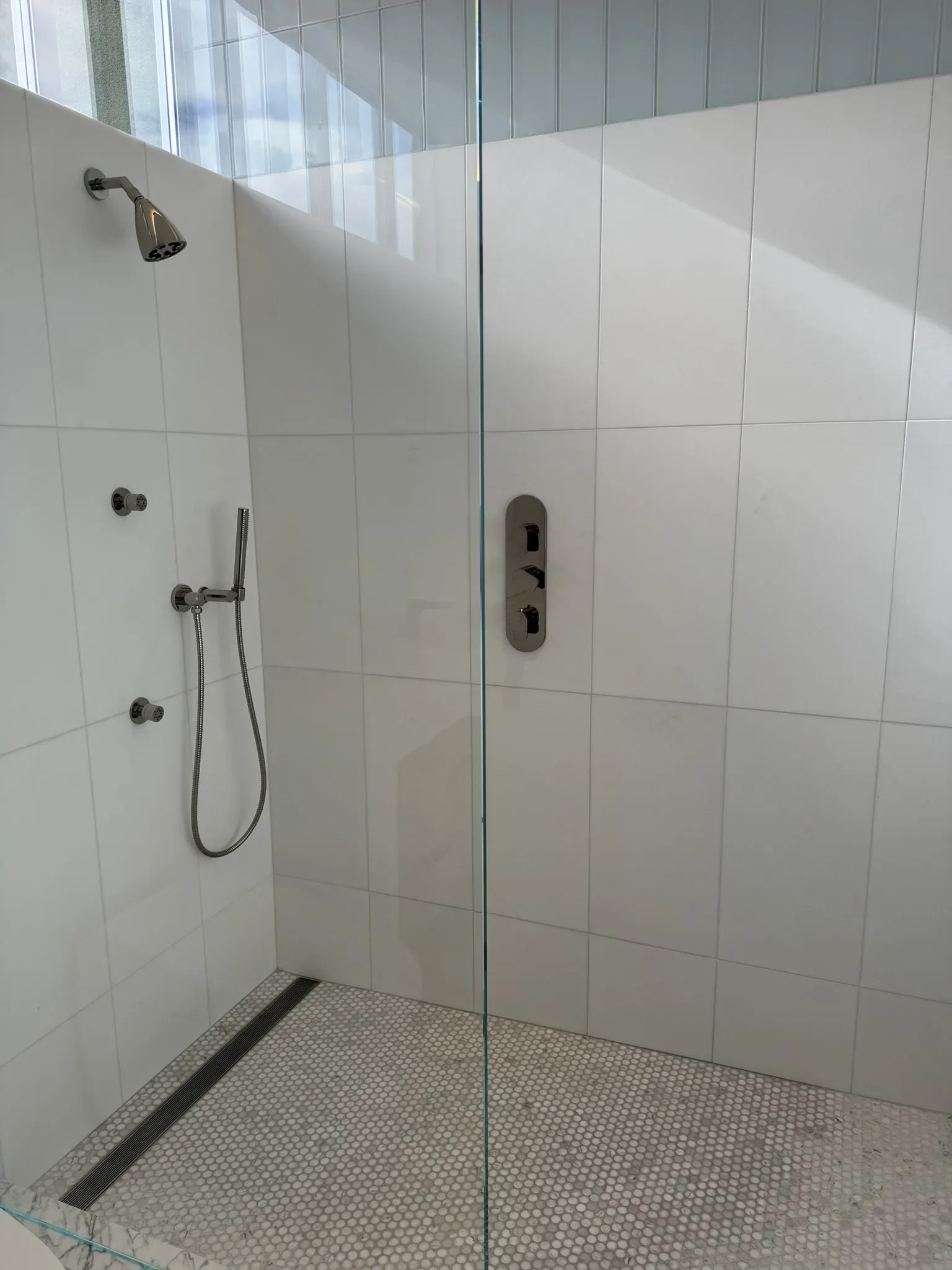 A shower with a glass door and a shower head.