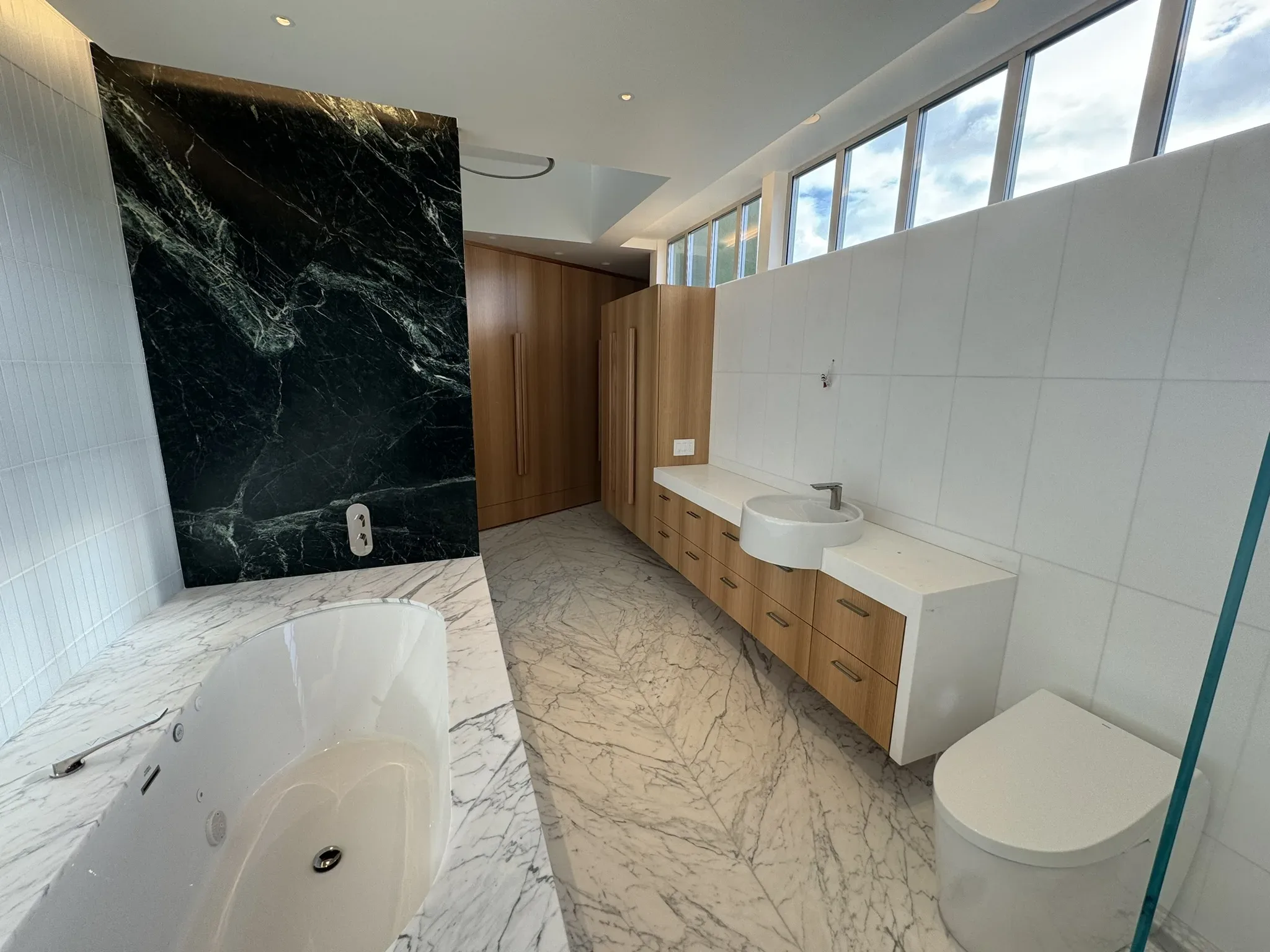 A modern bathroom with marble walls and a bathtub.