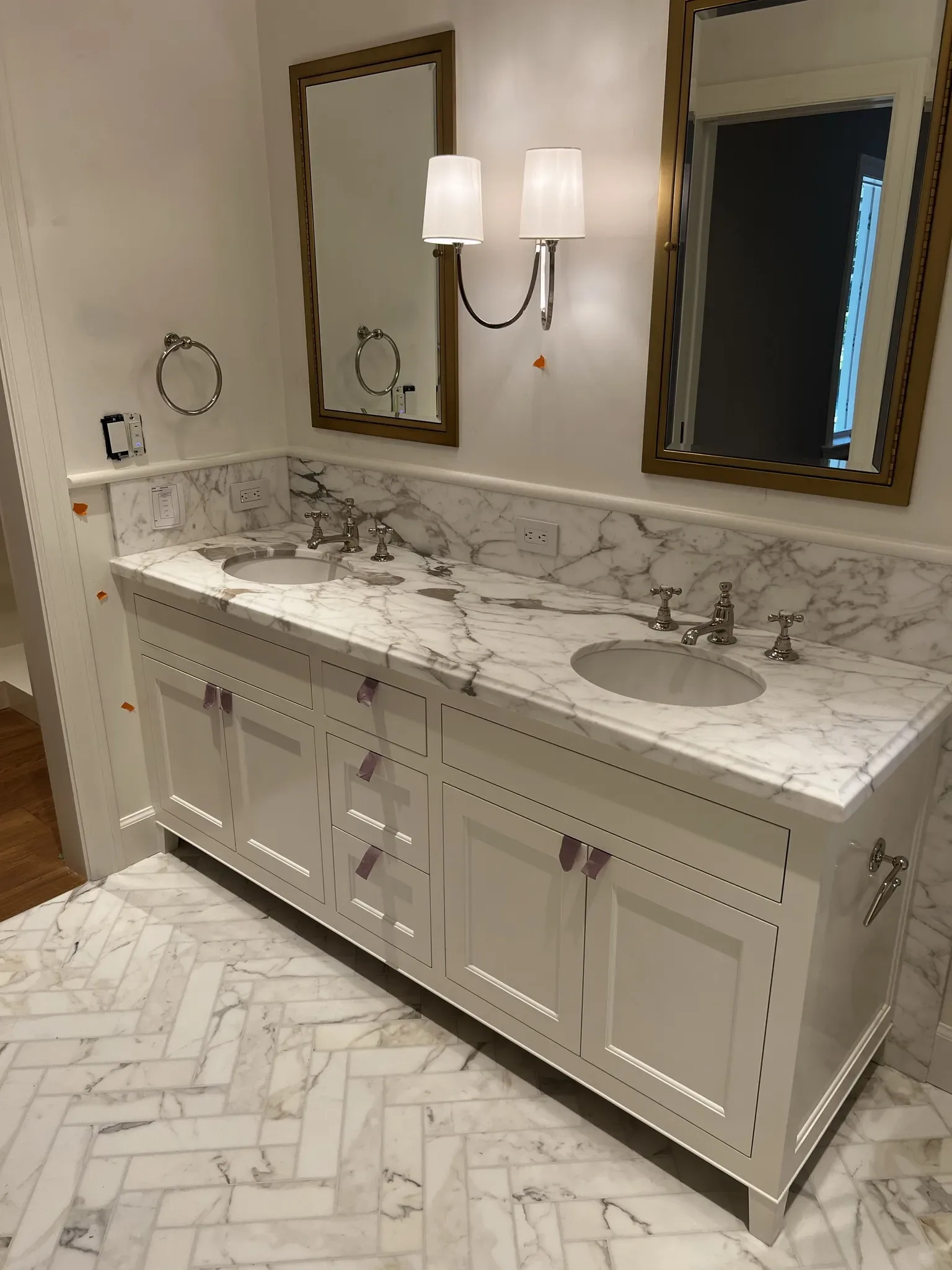 A white bathroom with marble counter tops and mirrors.