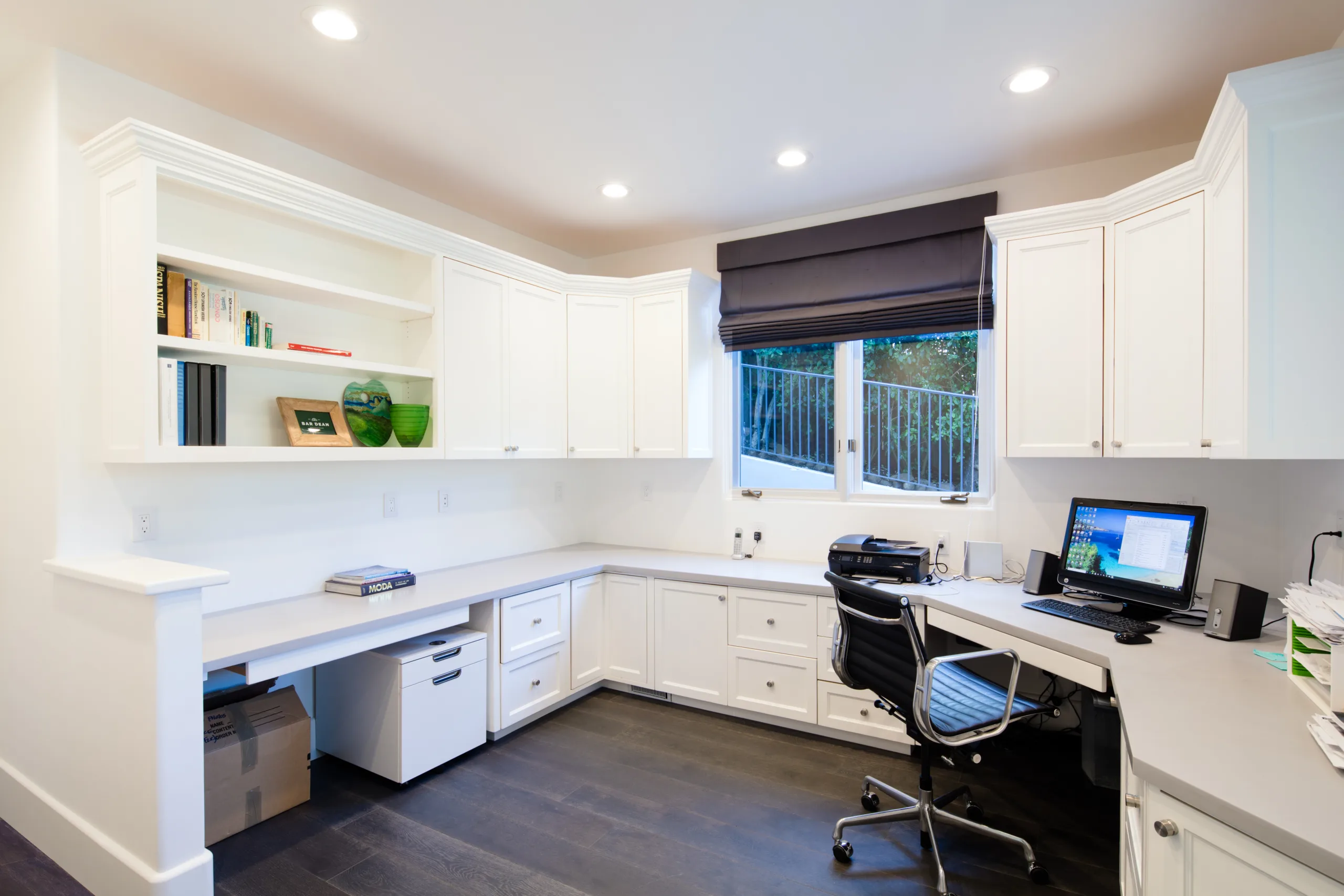 A home office with white cabinets and a desk.