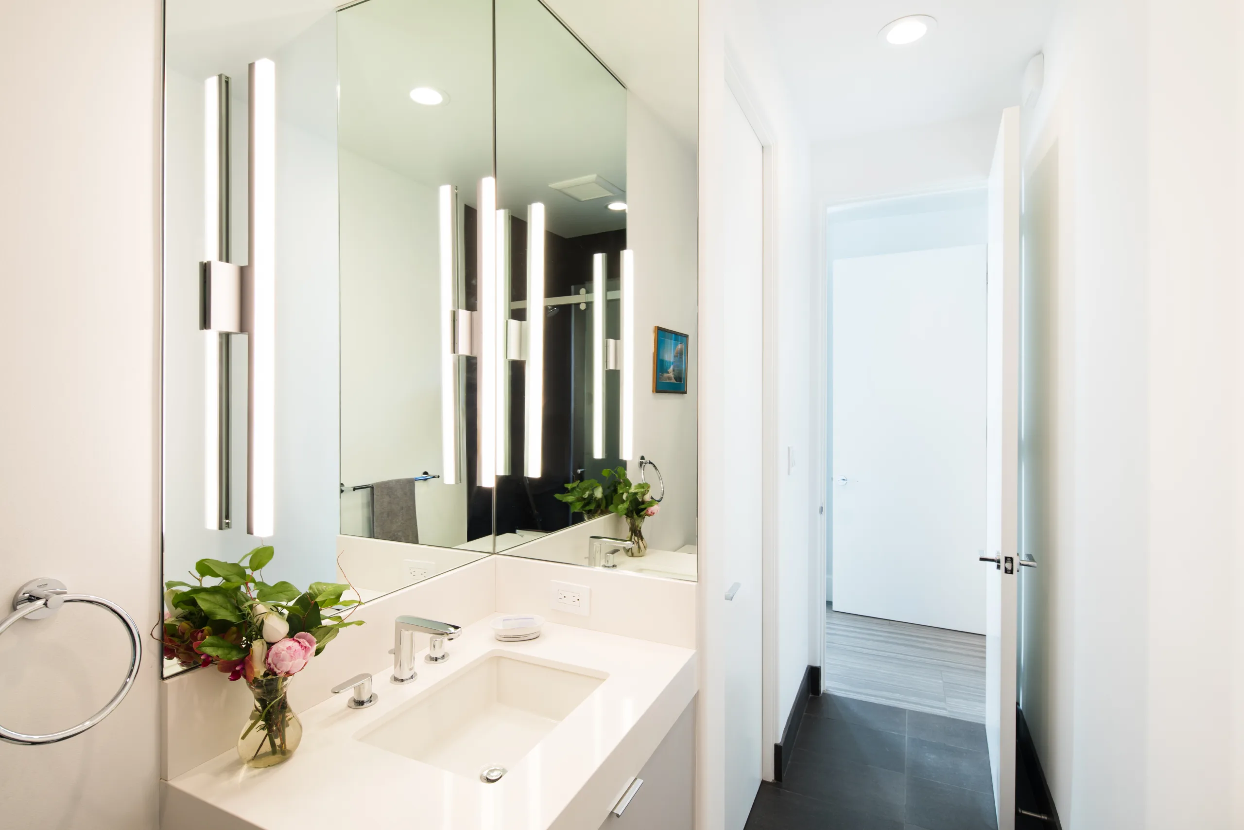 A modern bathroom with a white sink and mirror.